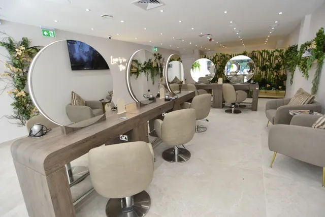 Salon with chairs and mirrors on the wall, a sofa with pillows, a table with various objects, plants, a television